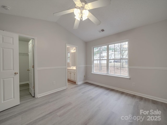 unfurnished bedroom featuring a walk in closet, ceiling fan, connected bathroom, a closet, and lofted ceiling