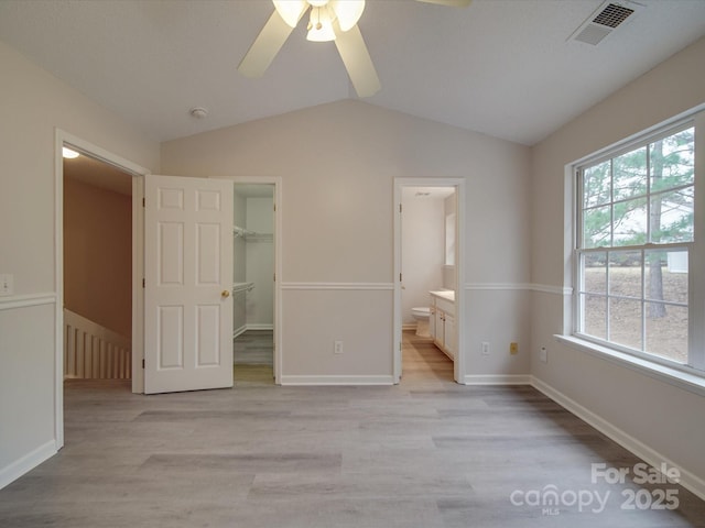 unfurnished bedroom with ensuite bathroom, light hardwood / wood-style flooring, ceiling fan, a spacious closet, and a closet