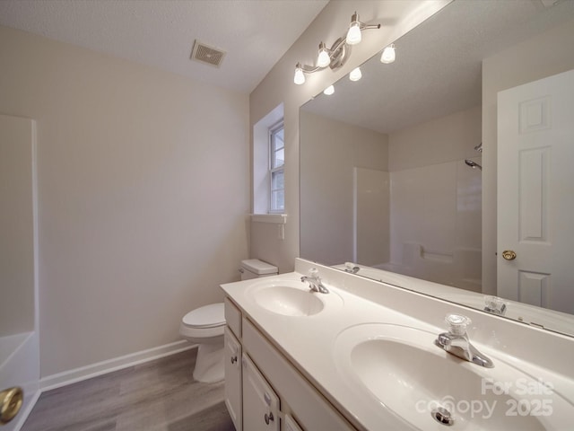 bathroom featuring vanity, a textured ceiling, a shower, hardwood / wood-style flooring, and toilet