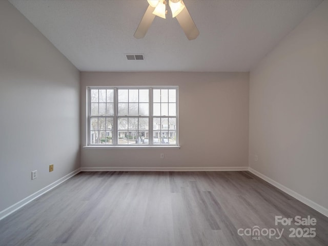 empty room with ceiling fan, light hardwood / wood-style floors, and a textured ceiling