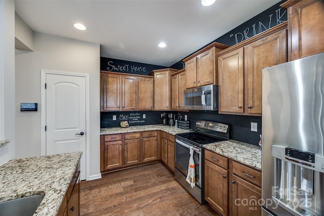 kitchen with backsplash, sink, light stone countertops, appliances with stainless steel finishes, and dark hardwood / wood-style flooring