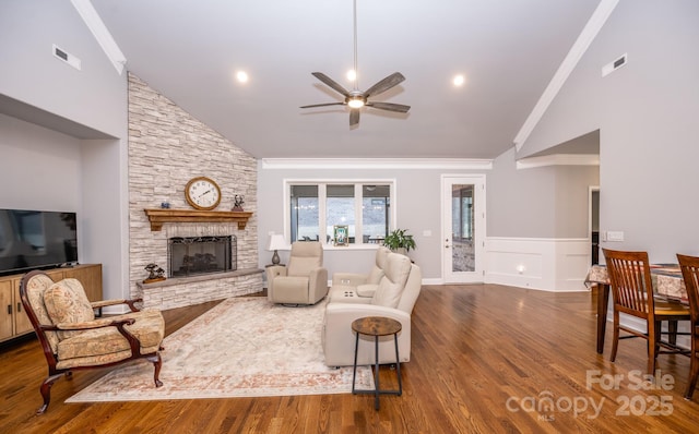 living room featuring ceiling fan, a stone fireplace, hardwood / wood-style floors, lofted ceiling, and ornamental molding