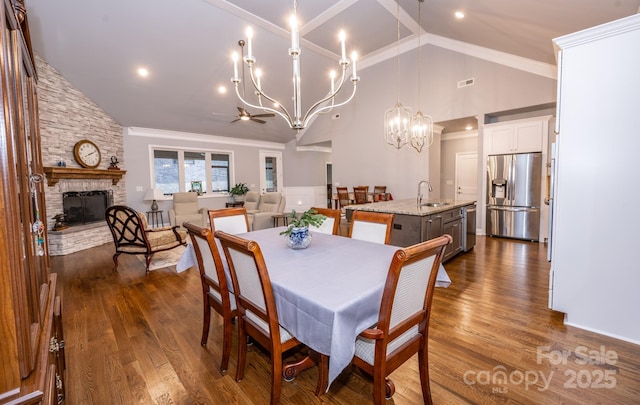 dining space featuring a fireplace, ceiling fan with notable chandelier, dark hardwood / wood-style floors, and sink