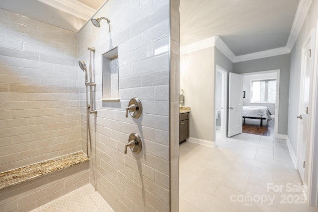 bathroom featuring tile patterned flooring, vanity, a tile shower, and ornamental molding