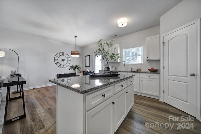 kitchen with white cabinets, a center island, dark stone counters, and pendant lighting