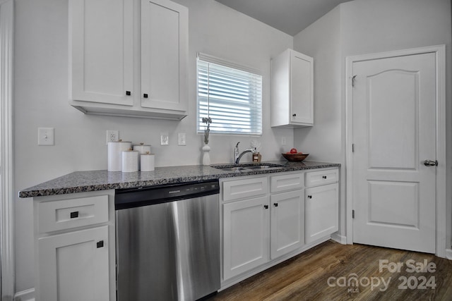 kitchen with stainless steel dishwasher, sink, white cabinets, and dark stone countertops