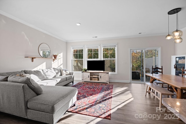 living area with visible vents, wood finished floors, baseboards, and ornamental molding