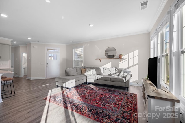 living room featuring a wealth of natural light, visible vents, wood finished floors, and crown molding