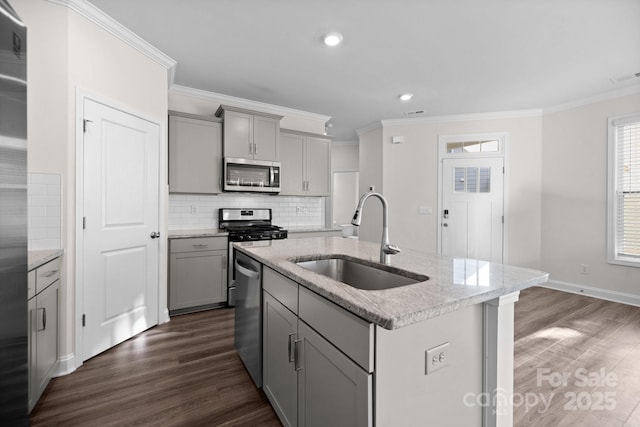 kitchen with an island with sink, gray cabinets, a sink, dark wood finished floors, and stainless steel appliances