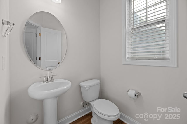 bathroom with baseboards, toilet, a healthy amount of sunlight, and wood finished floors