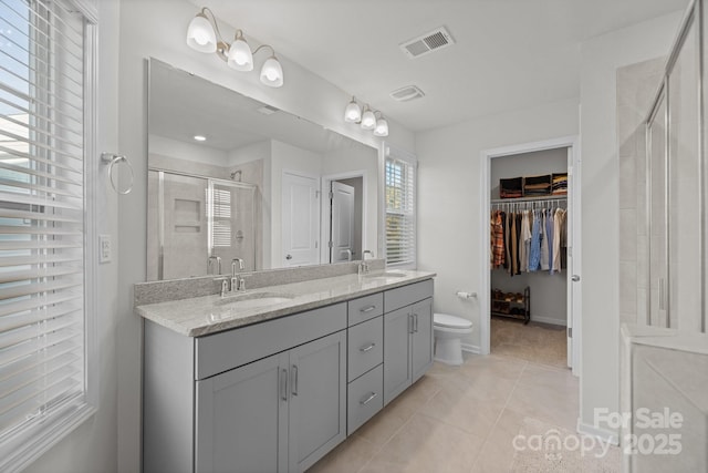 full bathroom with double vanity, a stall shower, visible vents, and a sink