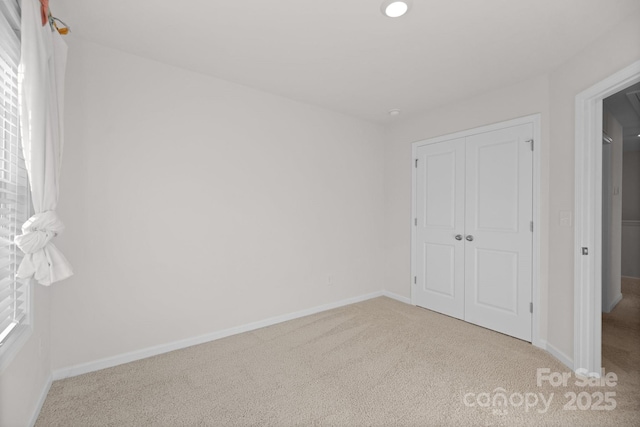 unfurnished bedroom with a closet, multiple windows, baseboards, and carpet floors