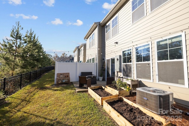 view of side of home featuring a garden, central air condition unit, a lawn, and a fenced backyard