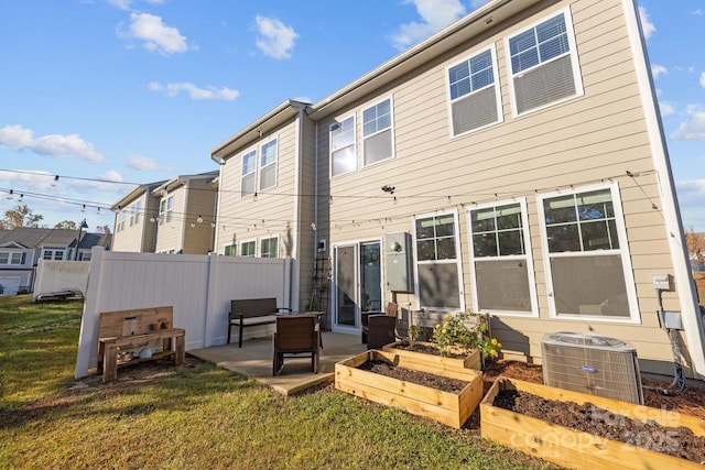 rear view of property featuring a lawn, fence, cooling unit, a garden, and a patio area