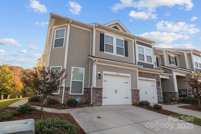 multi unit property with a garage, stone siding, and concrete driveway