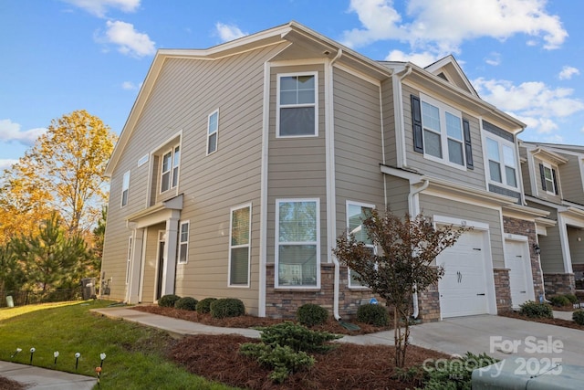 multi unit property with stone siding, a front yard, concrete driveway, and an attached garage