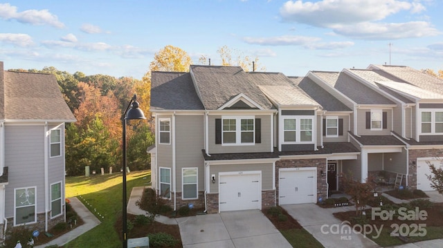 view of property featuring stone siding, driveway, an attached garage, and a front lawn