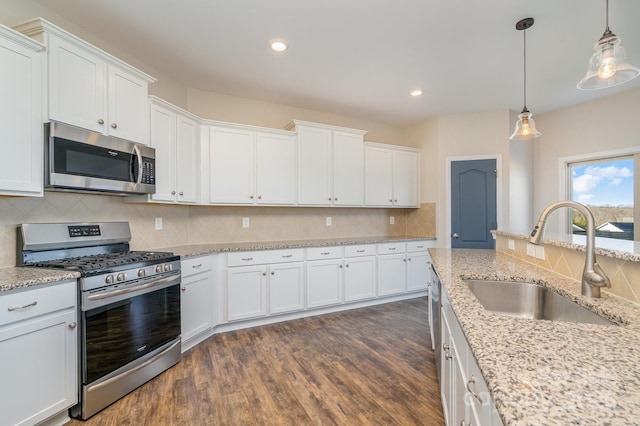 kitchen featuring white cabinets, hanging light fixtures, sink, and appliances with stainless steel finishes