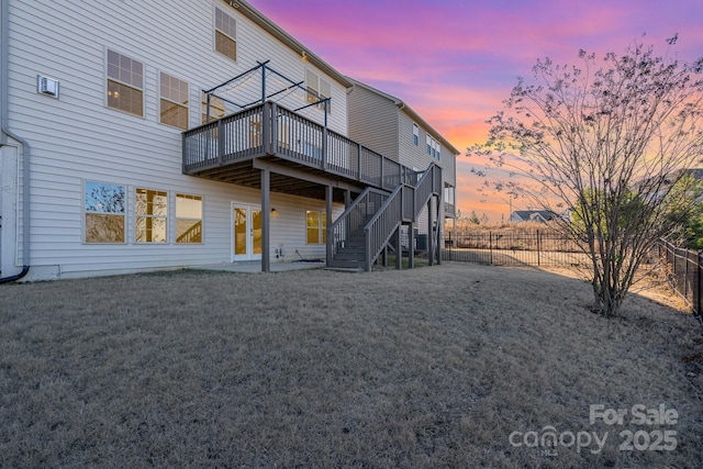 back house at dusk with french doors, a yard, a deck, and a patio