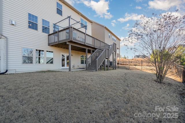 rear view of property featuring a lawn, a patio area, and a wooden deck