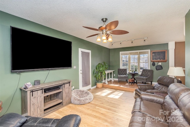 living room with a textured ceiling, ceiling fan, rail lighting, and wood-type flooring