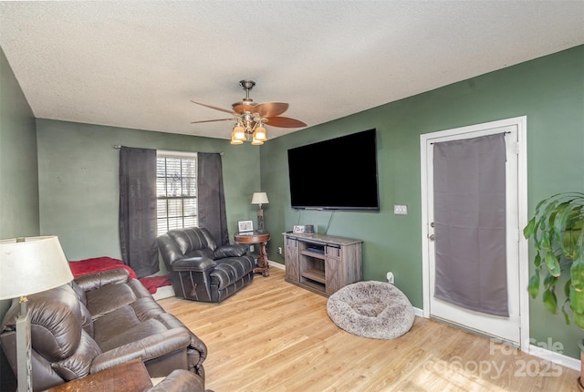 living room with light hardwood / wood-style floors, a textured ceiling, and ceiling fan