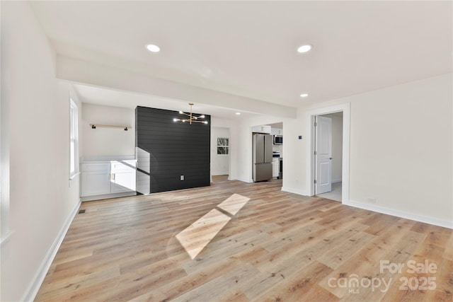 unfurnished living room featuring light hardwood / wood-style floors and a chandelier