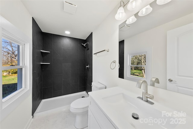 bathroom featuring vanity, toilet, and a tile shower