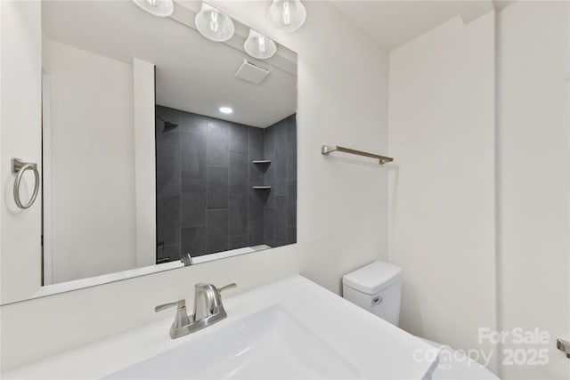 bathroom featuring a tile shower, toilet, and sink