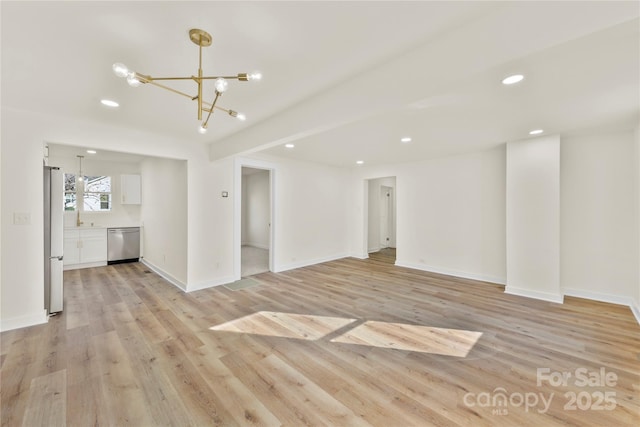 unfurnished living room with a notable chandelier, light wood-type flooring, and sink