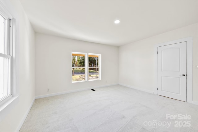 spare room featuring light colored carpet and plenty of natural light