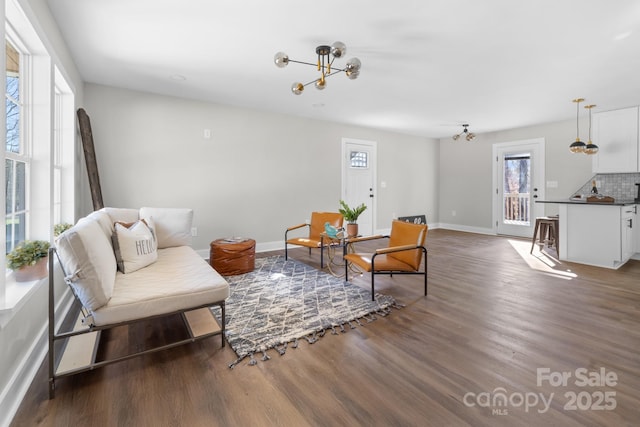 living area with a notable chandelier, a healthy amount of sunlight, and dark hardwood / wood-style floors