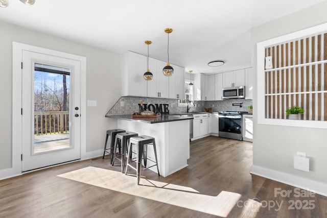 kitchen with kitchen peninsula, a breakfast bar, stainless steel appliances, pendant lighting, and white cabinets