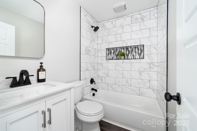 full bathroom with vanity, tiled shower / bath combo, and toilet