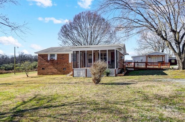 rear view of property with a lawn, a deck, and a sunroom