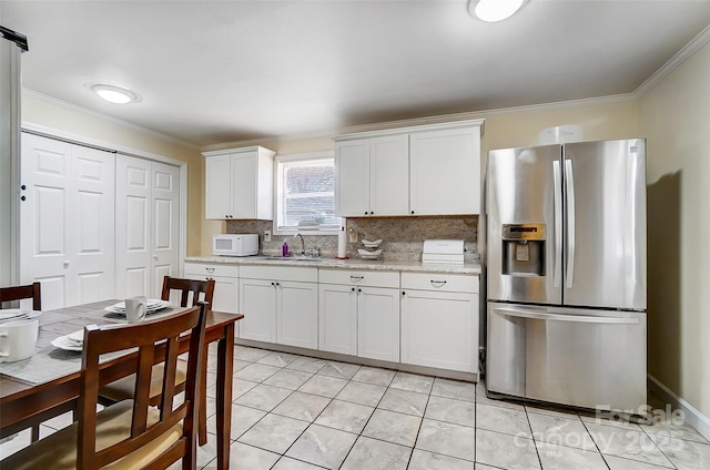 kitchen with sink, white cabinetry, tasteful backsplash, and stainless steel fridge