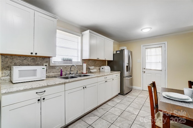 kitchen featuring white cabinets, light stone countertops, light tile patterned floors, and sink