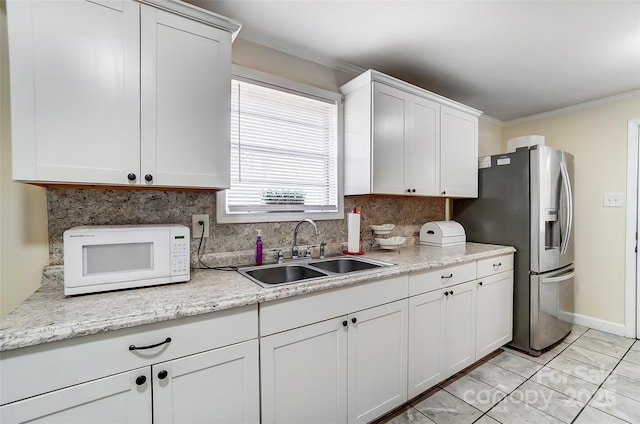 kitchen with light tile patterned floors, stainless steel refrigerator with ice dispenser, white cabinets, ornamental molding, and sink