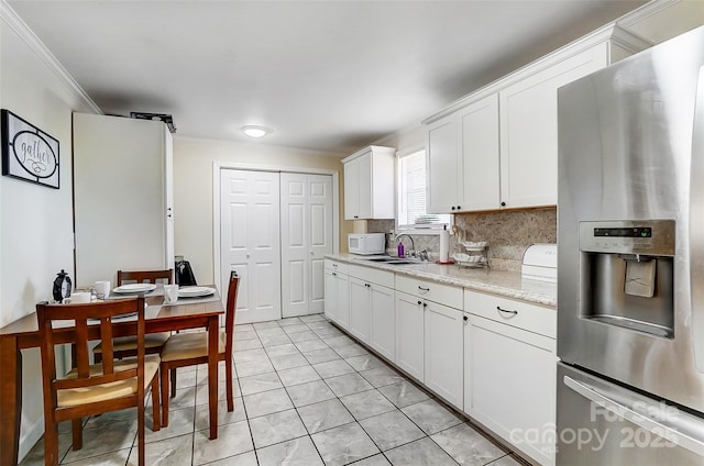 kitchen with stainless steel fridge with ice dispenser, ornamental molding, light stone counters, sink, and white cabinetry