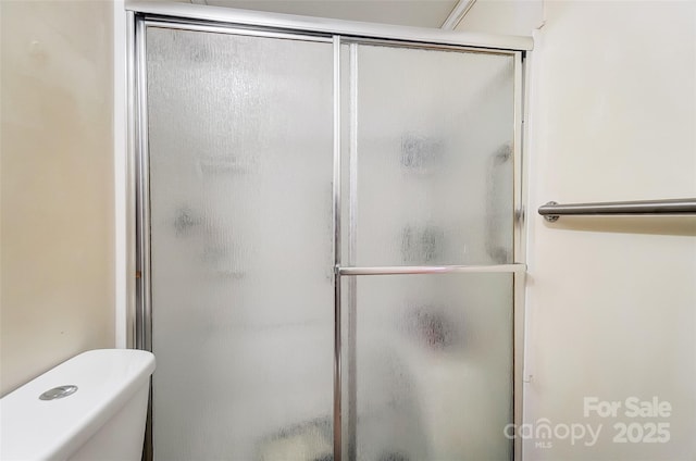 bathroom with a shower with shower door and toilet