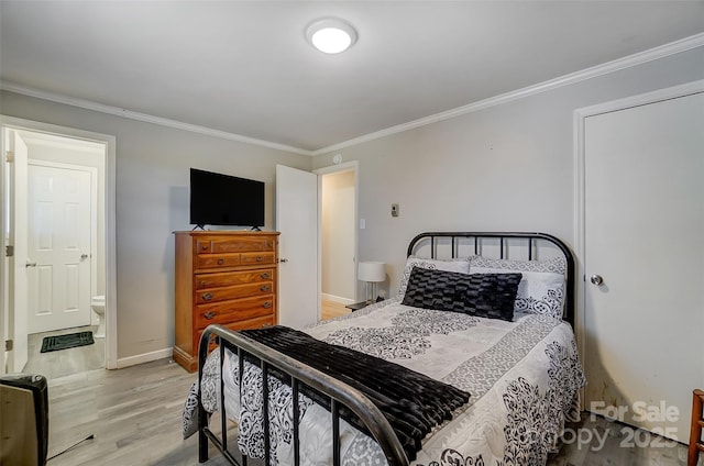 bedroom featuring ensuite bathroom, ornamental molding, and light hardwood / wood-style flooring