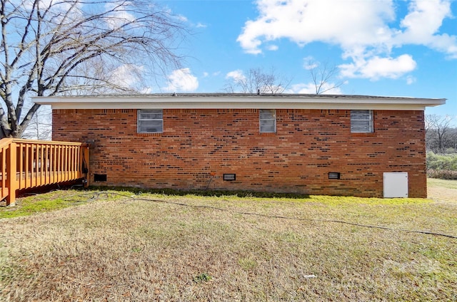 view of side of home featuring a yard and a wooden deck