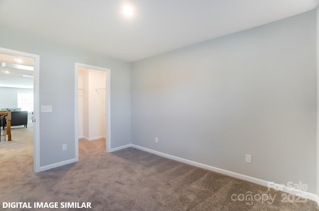 unfurnished bedroom with a walk in closet, light carpet, and a closet