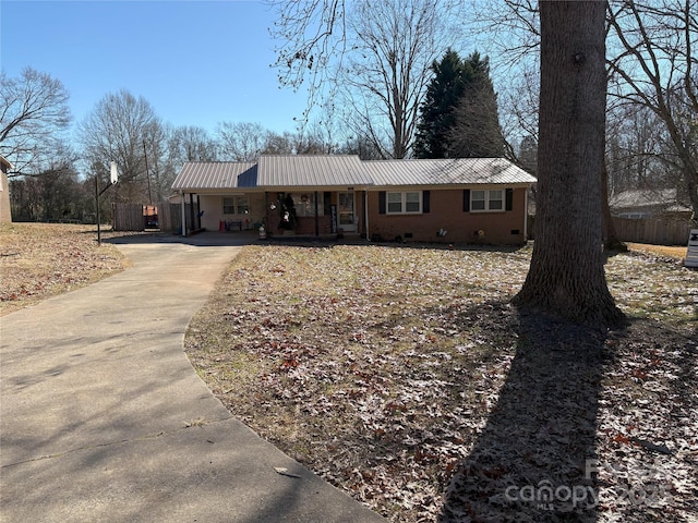 ranch-style house with concrete driveway, metal roof, crawl space, covered porch, and brick siding