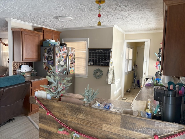 kitchen with a textured ceiling, stainless steel fridge, and crown molding