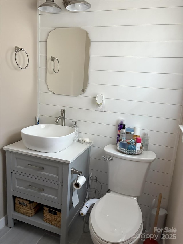 bathroom featuring vanity, toilet, and wood walls