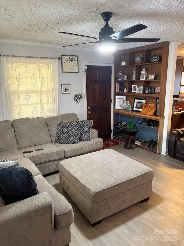 living room with a textured ceiling, a ceiling fan, and wood finished floors