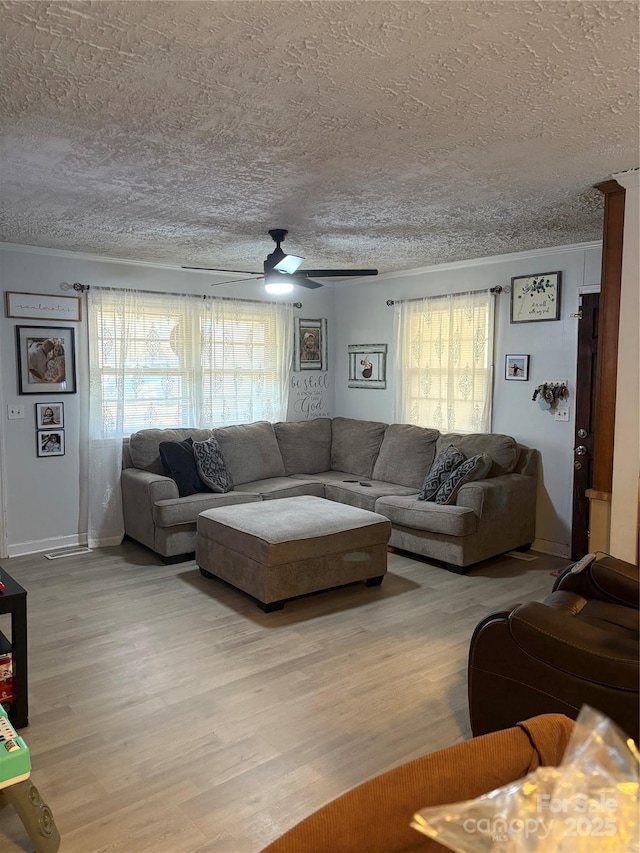 living room featuring a textured ceiling, ornamental molding, a ceiling fan, and light wood-style floors
