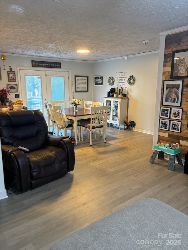 living area with a textured ceiling, baseboards, and wood finished floors