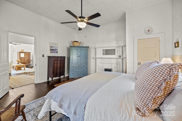 bedroom with crown molding, dark wood-type flooring, and ceiling fan